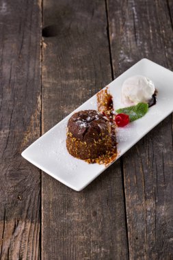 Kirazlı çikolatalı şekerleme, beyaz tabakta naneli dondurma kepçesi ve tahta arka plan. Dikey yönelim