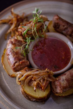 Izgara kuzu sosisi, dilimlenmiş sosis, acılı patates dilimli kızarmış soğan. Ahşap arkaplan.