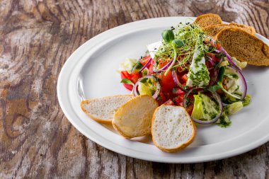 Soğanlı salata, domates, peynir, marul, pesto, mung fasulyesi salatası, ahşap bir tabakta taze filizler ve ekmek.
