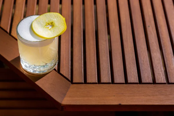 Cocktail with ice, apple and froth in a glass on the table