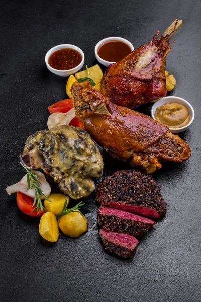 Fried lamb steak on the bone, beef steak, beef on the bone with potatoes, tomatoes, garlic rosemary, young shoots, red sauce on a stone background. Vertical orientation