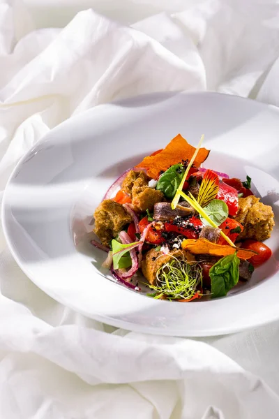 Caesar salad with onions, bread, young shoots, basil, and cheese in a plate on a light background
