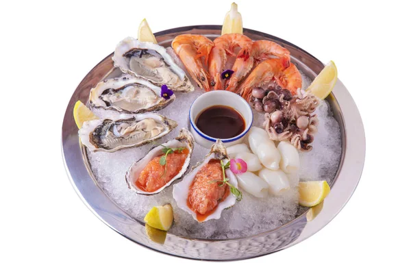 Oysters, shrimps, squids, octopus and minced salmon with pea sprouts, sauce, lemon on ice in a plate on a white plate