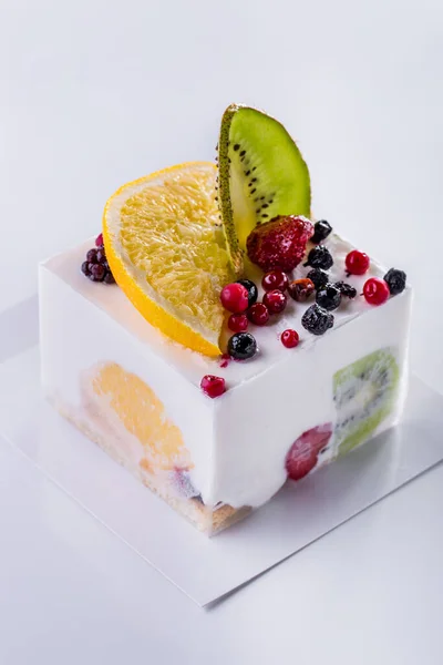 Milk dessert with kiwi, orange, cranberry, strawberry, currant on a light background. Vertical Orientation