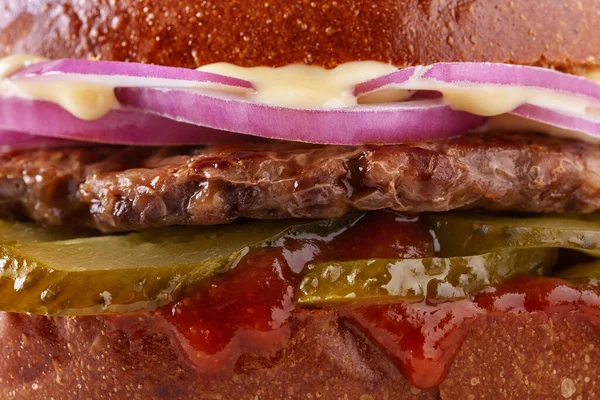 Hamburger with pork cutlet, salad, onion, pickled cucumbers, ketchup and sauce on a white background