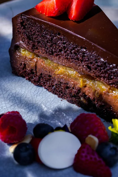Piece of cake with strawberries, raspberries, blueberries, meringues, jam and chocolate in a plate