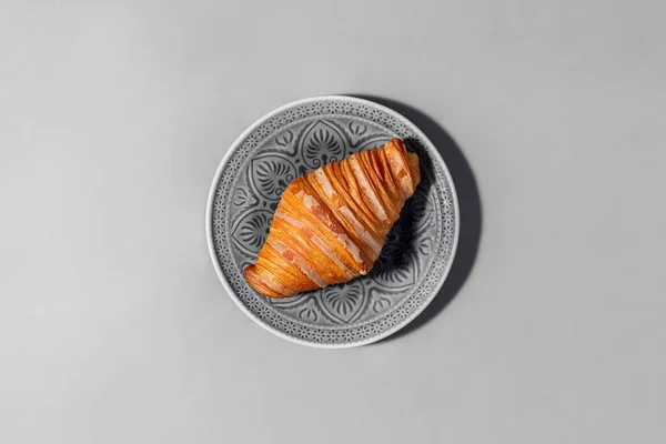 Croissant Bez Nadzienia Croissant Leży Szarej Ceramicznej Płytce Wzorem Talerz — Zdjęcie stockowe