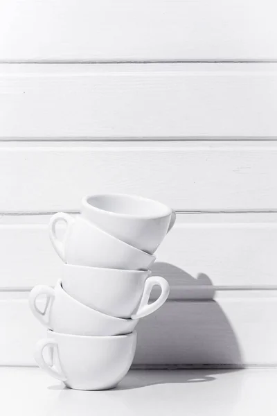 Tea cups standing on top of each other on white table and white wood background