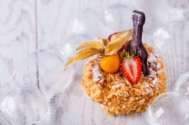 Round napoleon slice with physalis, raspberries, strawberries and chocolate guitar on a white background. Horizontal orientation
