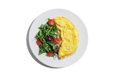 Omelet with arugula tomatoes and basil in a plate on a white plate
