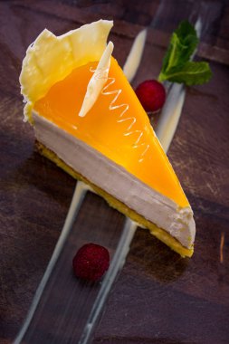 Narenciye kremalı peynir güveci, bir parça çikolata, ahududu ve nane şekeri masanın üzerinde duruyor. Dikey yönelim