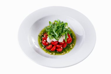 Salad with tomatoes, arugula, mozzarella and sauce in a plate with sauce on a wooden table