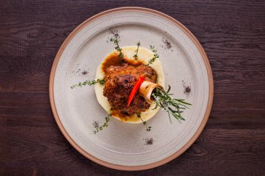 Kemiğe kuzu rostosu, kekik, biberiye, biber ve ahşap bir zeminde patates püresi. Yatay yönelim