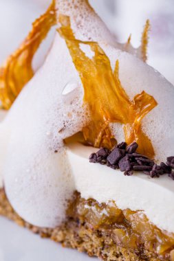 Pie with cheese, jam, chocolate, milk froth and caramel on a white round plate with a cup of coffee. Vertical orientation