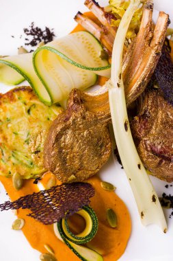 Altın yapraklı pirzola, sos, kabak, tohum ve beyaz tabakta dantel cips. Dikey yönelim