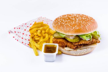 Burger with sesame bun, cutlet, salad, white sauce, pickled cucumbers and cheese with fries and sauce on a white background. Horizontal orientation