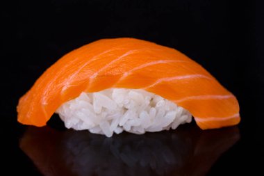 Roll with salmon and rice on a dark mirror background