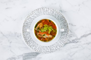 Balık çorbası, maydanoz, havuç ve biber mermer bir masada bir tabakta