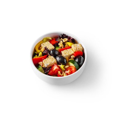 Salad with cheese, sesame seeds, tomatoes, olives, lettuce, cucumbers and peppers in a bowl on a white background
