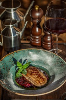 Nane, reçel ve pudra şekerli kızarmış et parçası bir bardak kırmızı şarapla yuvarlak bir tabakta. Dikey yönelim