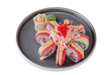 Rolls with salmon, tuna, cabbage, flying fish caviar, rice, sauce, cucumber, nori, wasabi, ginger on a platter on a white plate