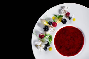 Blueberry, raspberry, flower petal, blackberry, and mint jam on a white plate. Horizontal orientation