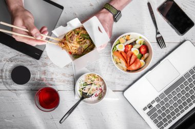 Salad with salmon, egg, tomatoes, croutons, cheese and salad in a paper box, a man who eats corn, spaghetti, pork, asparagus beans, onions, pepper, chopsticks and a third paper box with okroshka spoon with radishes, cucumbers, onions, eggs and ham st