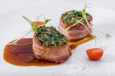 Domatesli kızarmış et parçaları taze bezelye filizleri, sos ve yuvarlak tabakta maydanoz. Yatay yönelim