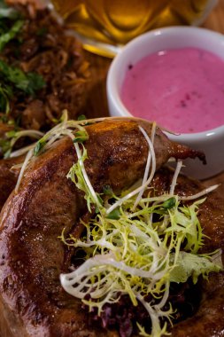 Genç filizli kızarmış sosis, sos, dilimlenmiş marul ve beyaz tabakta bir bardak light bira. Dikey yönelim