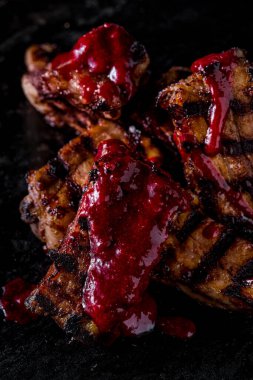 Grilled pork ribs marinated with cherry sauce. The ribs lie on a dark wooden background. Close-up