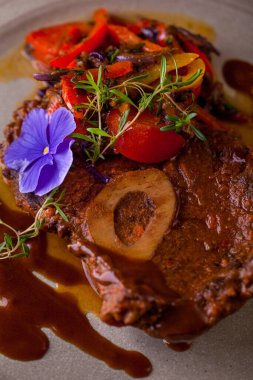 Kemiklerde kızarmış et, çiçek yaprakları, biberiye, sos, domates, biber. Dikey yönelim