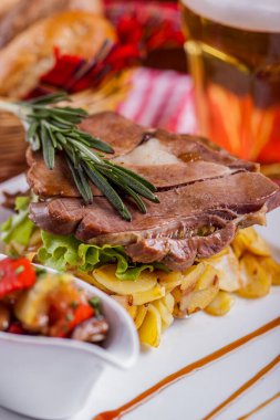 Biberiye, patates, salata ve sebzelerle birlikte bir sepet ekmek ve bir kupa light birayla kemiğe kızarmış et. Dikey yönelim