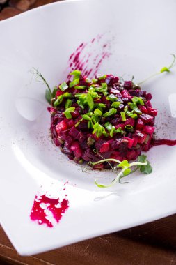 Soğanlı salata, bezelye filizi, pancar ve patatesler ahşap bir masada bir tabakta.