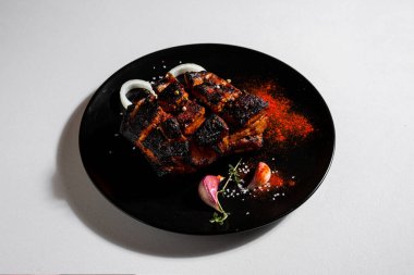 Fried beef meat with peppercorns, onions, paprika, salt, thyme and garlic in a plate on a white background