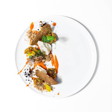 Kabaktan katran, domates, paprika ve kişniş. Yakınlarda mikroyeşil fesleğenler, ayçiçeği tohumlu çavdar ekmeği cipsleri, havuç püresi sosu, ceviz ezmesi ve mozzarella parçaları var. Yemek beyaz bir tabakta, tabak beyaz bir tabakta duruyor.