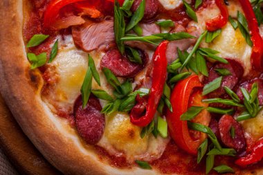 Pizza with cherry tomatoes, ham, salad and cheese on a wooden board on the table