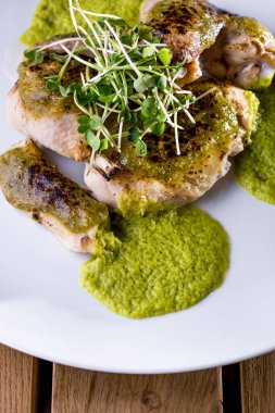 Kemiklerde çiğ tavuk, fasulye salatası ve yeşil soslu beyaz yuvarlak tabak. Dikey yönelim