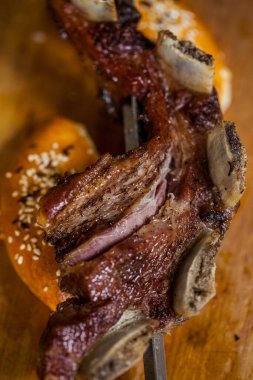 Lamb ribs on a skewer, grilled with buns sprinkled with sesame seeds. Food lies on a wooden board