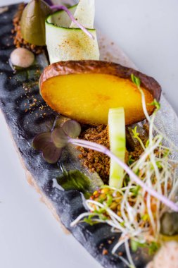 Kızarmış uskumru, patates, salatalık ve kocchini hafif arka planda beyaz yuvarlak bir tabakta. Dikey yönelim