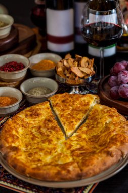 Tabağında peynir, üzüm, kurutulmuş elma, baharat ve bir bardak kırmızı şarap olan Khachapuri. Dikey yönelim 