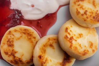 Pancakes in a plate with sour cream and jam on a plate