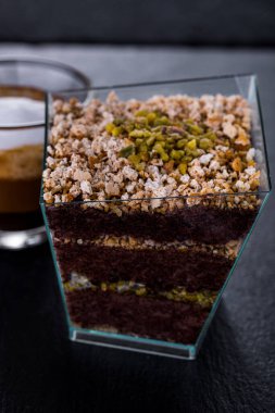 Dessert with crumb, layers of chocolate cake and a cup of coffee on a stone slab. Vertical orientation