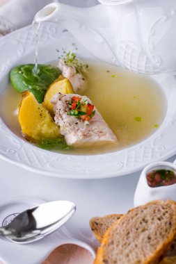 Et çorbası, taze filizler, maydanoz, ekşi krema, pancar ve havuç tabakta ve masada kaşık