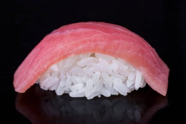 Roll with tuna and rice on a dark mirror background