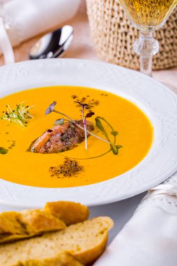 Somon etli çorba, ekmek tabağında taze filizler, bir kaşık ve masada bir bardak şarap