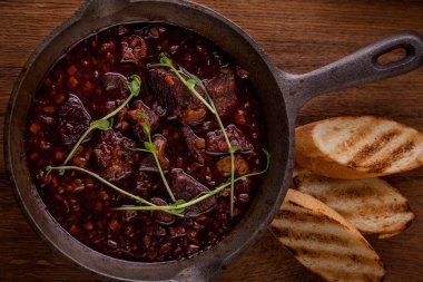 Kızarmış biftek, taze filizlenmiş sos, siyah tabakta salata. Dikey yönelim