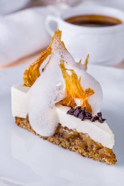 Pie with cheese, jam, chocolate, milk froth and caramel on a white round plate with a cup of coffee. Vertical orientation