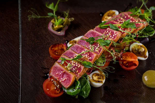 Susamlı kızarmış ton balığı, taze bezelye, haşlanmış yumurta, vişneli domates, ahşap bir masada yeşil soğan. Yatay yönelim