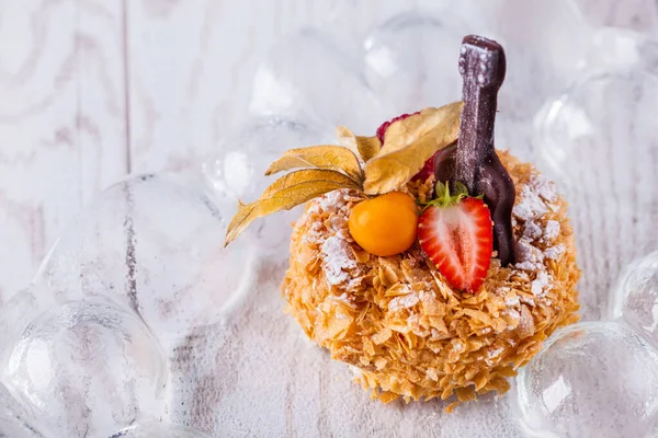 Round napoleon slice with physalis, raspberries, strawberries and chocolate guitar on a white background. Horizontal orientation