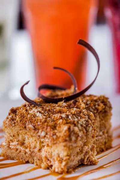 Bir dilim Napolyon keki, çikolata parçacıklı ve karamelli, yakın plan beyaz tabakta. Dikey yönelim